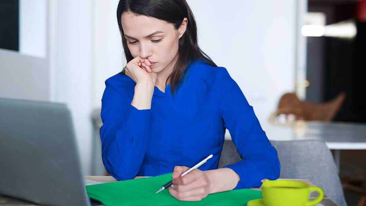 mulher sentada pensando e com caneta na mão escrevendo